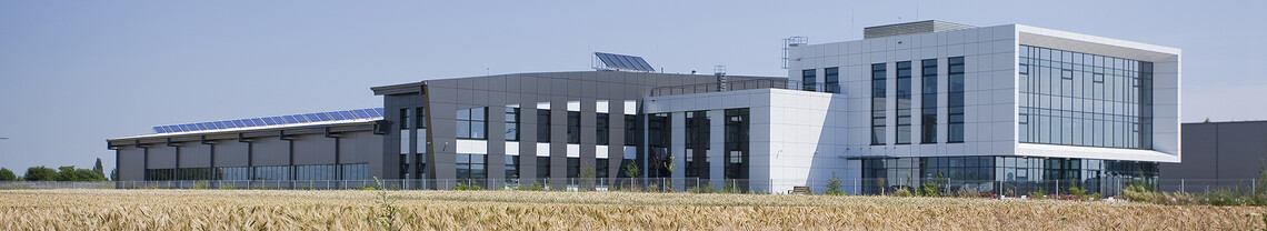Large manufacturing building with solar panels on the roof and an architectural office part